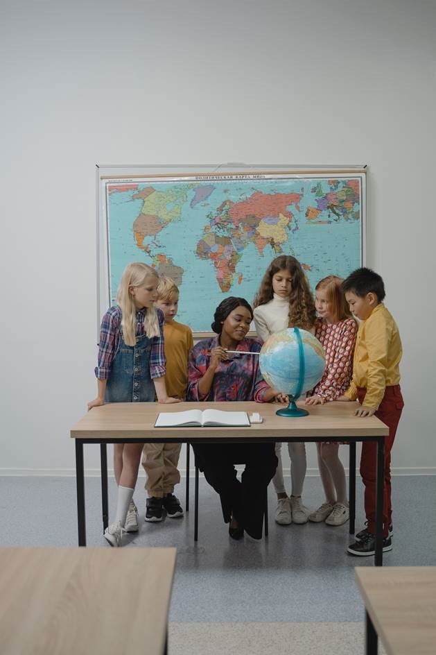 students look at the globe with their teacher